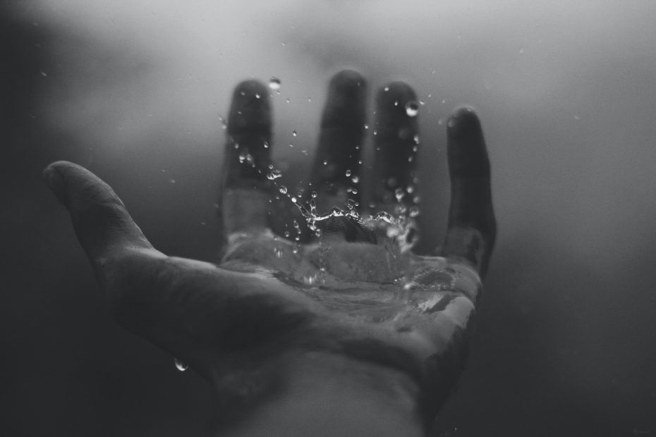 An image of rain falling on a person's hand